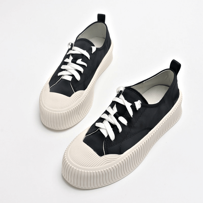 Women's black lace-up sports shoes with thick flat white soles, perfect for casual wear and comfort.